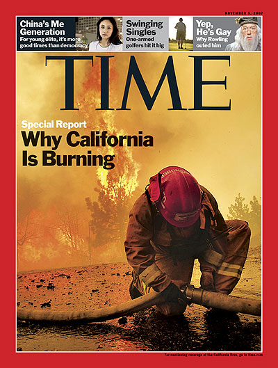 Photo of a fire fighter kneeling to connect a hose with the fire blazing behind him. Photograph by Robert Gauthier — Los Angeles <span style='font-style: italic'>Times</span>