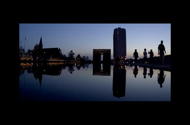 Visitor's silhouettes are mirrored in the reflecting pool as they stroll through the Oklahoma City National Memorial in Oklahoma City, Oklahoma