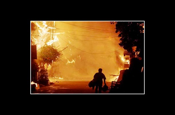 A resident flees with his belongings as a fire rages at a residential community in Cebu city in the Philippines