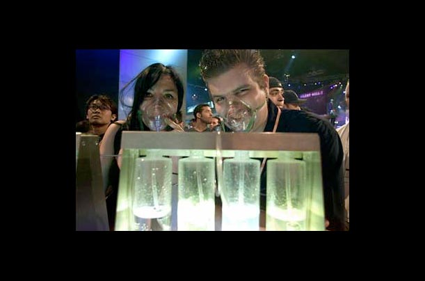 Two visitors breath oxygen from a dispenser bar on the first day of the Electronic Entertainment Expo 2001 at the Los Angeles Convention Center