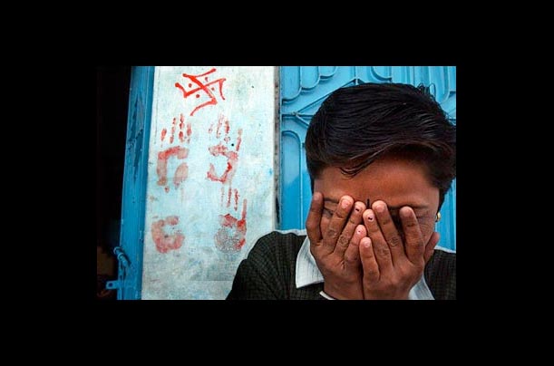 Nisha Rathad, 20, covers her face as she stands in front of her house next door to homes of Muslim neighbors who had been killed the day before in Ahmadabad, India