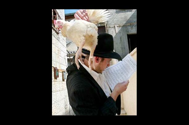 An Orthodox Jew swings a live chicken above his head as he recites prayers during the Kaparot ceremony in the Mea Shearim neighborhood of Jerusalem