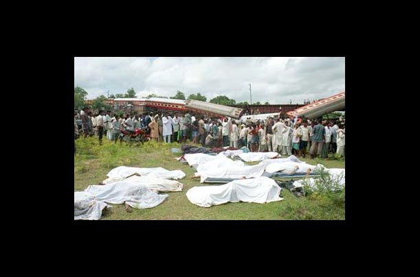 People crowd around the bodies of victims collected near a derailed train where at least 100 people are reported dead in India
