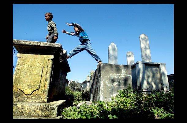 palestinian boys jump over gravestones in a cemetery in gaza city