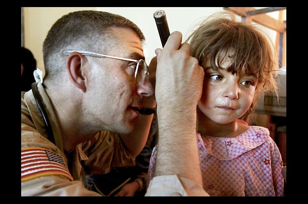 An Army medic examines a young girl at an impromptu medical clinic in Fadus, Iraq