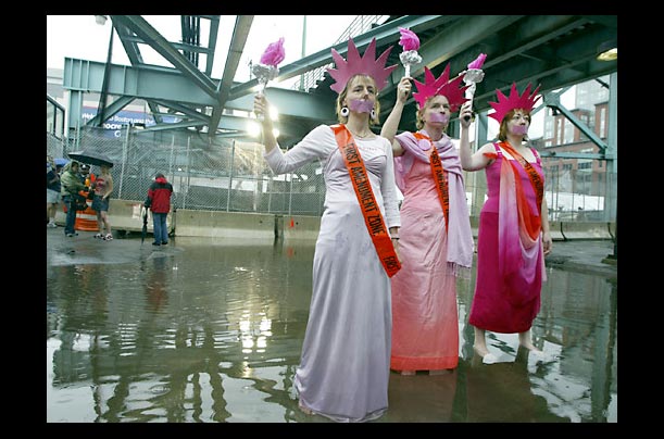 Protesters dressed as the Statue of Liberty, pose in a protest area outside the Fleet Center during the Democratic National Convention