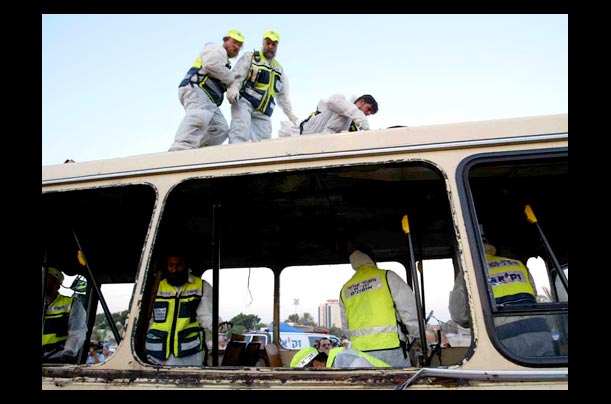 Israeli policemen and rescue workers inspect the scene of a suicide bombing in Beer Sheva, Israel