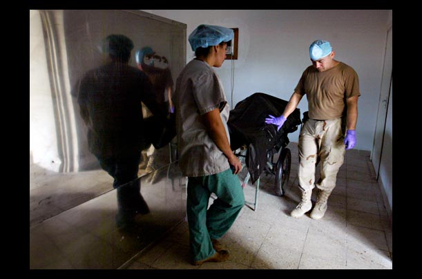 Army operating room nurses in Baghdad pause over the body of an American Marine who died from wounds suffered in Fallujah
