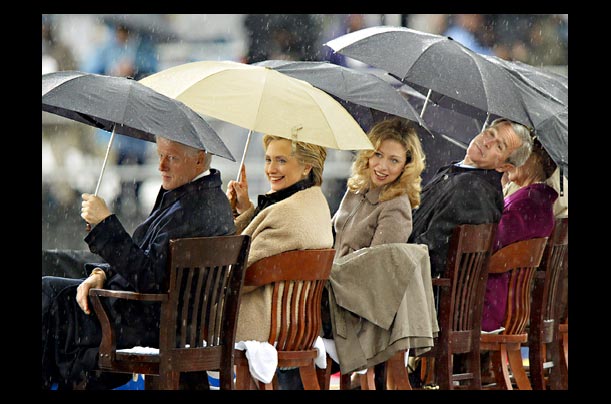 President George W. Bush, Bill Clinton, Hillary Rodham Clinton, and Chelsea Clinton hold umbrellas in the rain