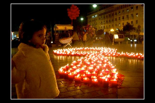a young girl stands in front of candles on world aids day in the greek port city of thessaloniki