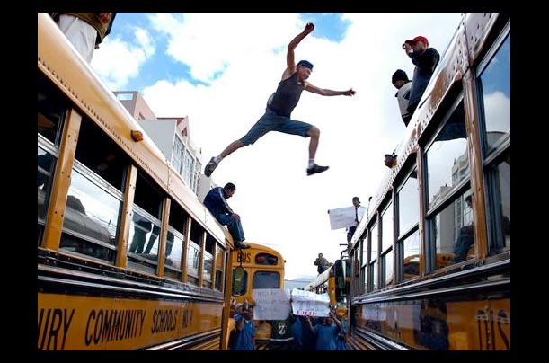 A driver jumps between school buses during a protest in Tegucigalpa, Honduras