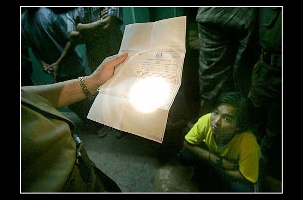 A migrant worker is apprehended during an immigration raid in Kuala Lumpur, Malaysia