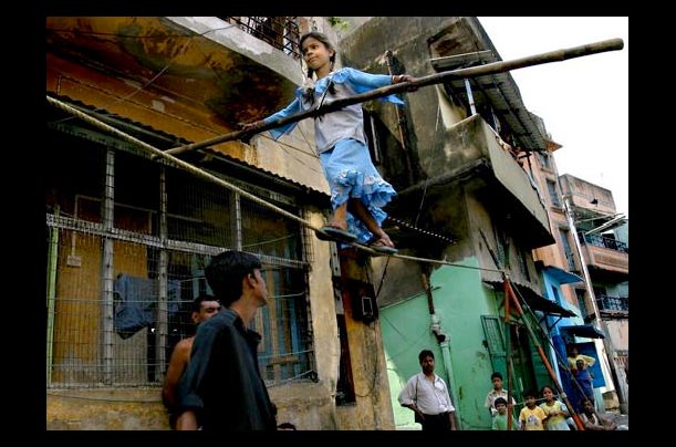 a young street circus performer  walks a tightrope in Gujarat, India