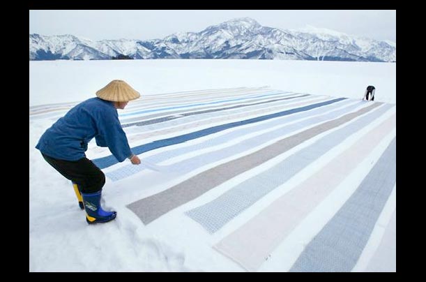 a weaver places kimono fabric on snow in the mountain village of Shiozawa, famous for 