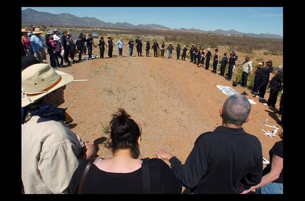 Participants of a vigil organized by the peace group Women in Black join hands and sing Give Peace a Chance at the U.S. and Mexico border