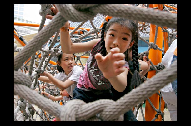 school children work their way through a playground rope maze in shanghai, china