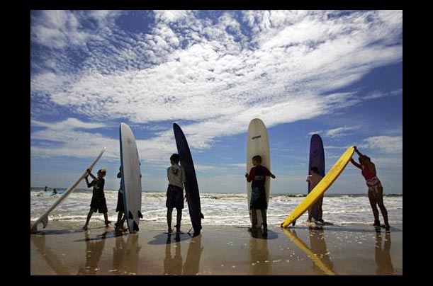 Surfers line up along Daytonia Beach at a surfing school