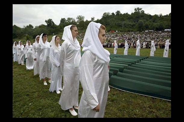 Choir singers perform in front of coffins of Srebrenica massacre victims during a memorial of the 10th anniversary of the Srebrenica Massacre in Bosnia-Herzegovina