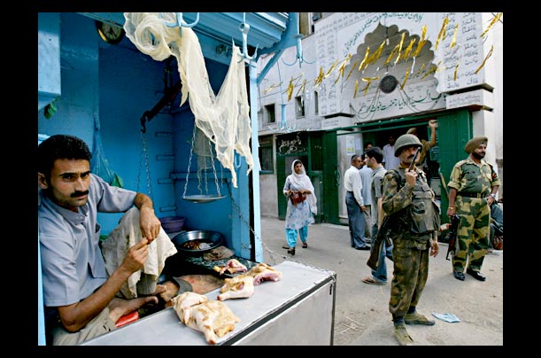 A shopkeeper in Kashmir looks on as soldiers guard a street near his store A shopkeeper in Kashmir looks on as soldiers guard a street near his store