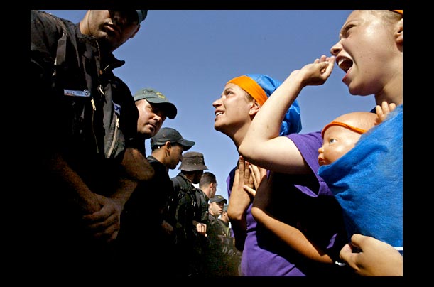 Israeli army soldiers hold plastic dolls acting as Jewish settlers with babies to confront Israeli police during training