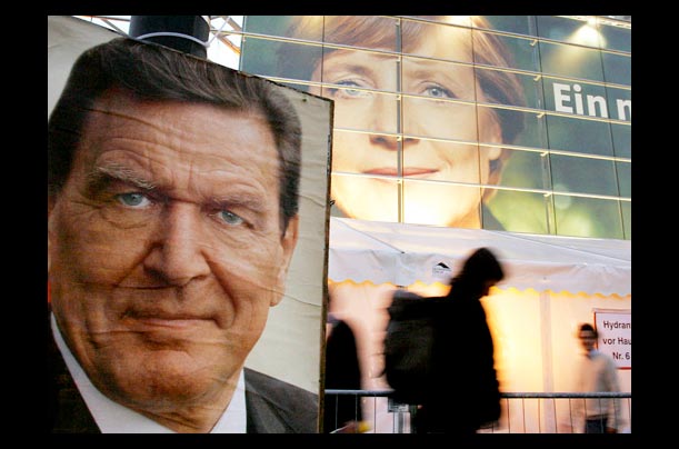 An election billboard of German chancellor Gerhard Schroeder is seen in front of the giant portrait of Christian Democratic Union leader Angela Merkel