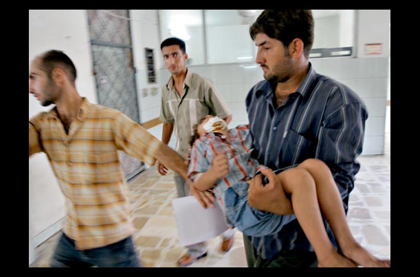 An Iraqi man carries a wounded child into an emergency room in Baghdad, following a suicide attack on the edge of the Green Zone