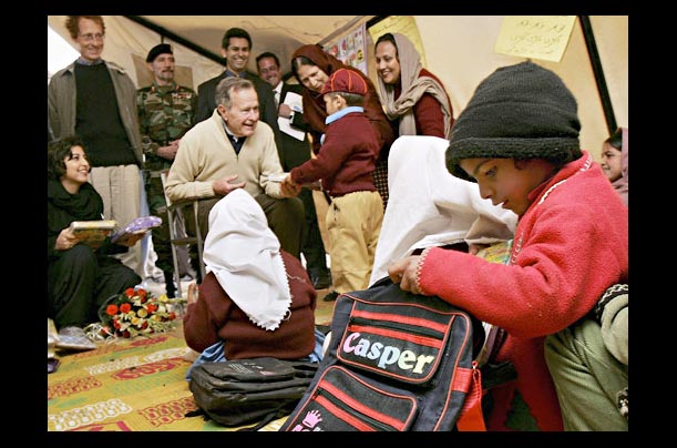 Former U.S. President George Bush hands out school supplies to first graders living in a tent camp on the outskirts of Islamabad after losing their homes to an earthquake