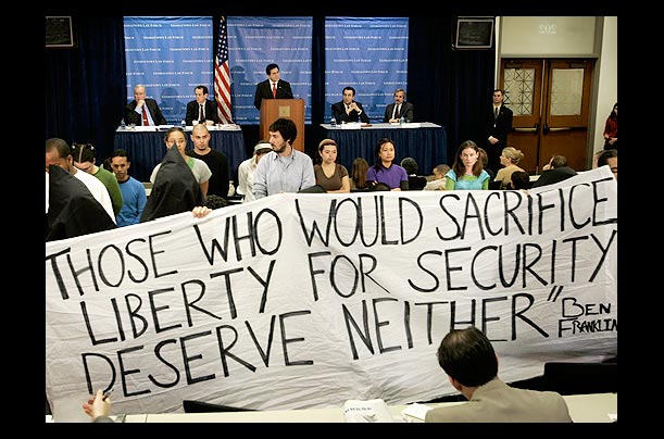Protesters unfurl a banner as Attorney General Alberto Gonzales speaks at Georgetown University Law School