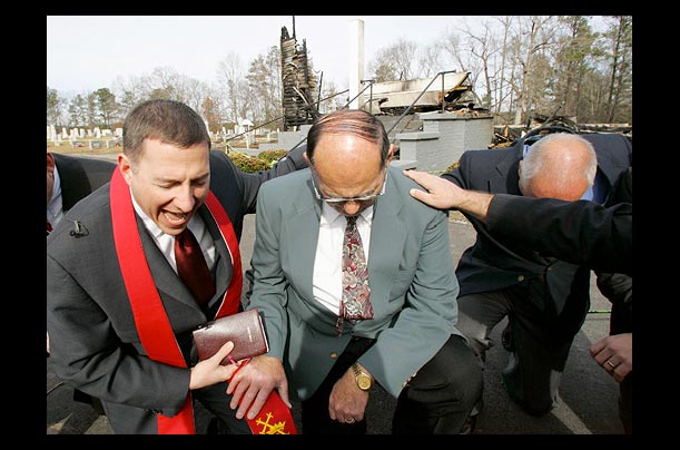 Reverend Rob Schenck, President of the National Clergy Council, prays with clergymen in front of a destroyed church in Lawley, Alabama, following arson attacks