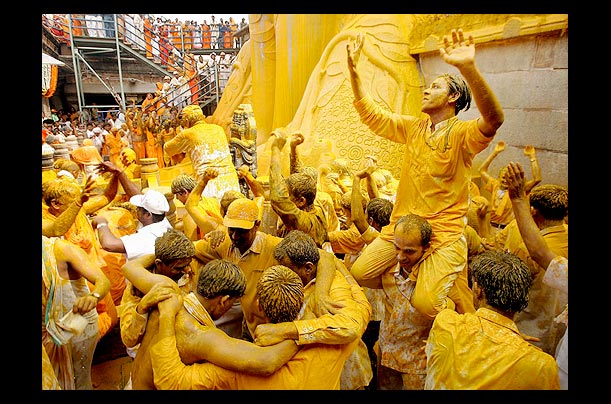 Jain devotees dance as they are soaked in liquid saffron poured over the statue of their sage, Gomateswara, in Shravanabelagola, India