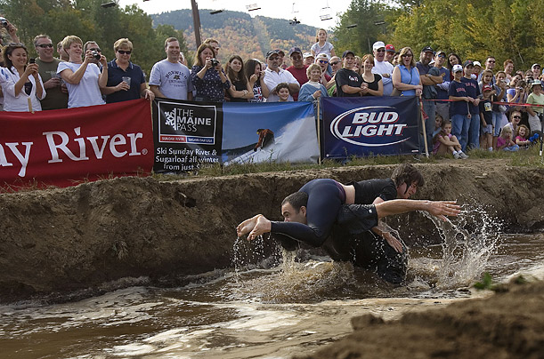 Ivan Wolkind (L) and Leah Lesch (R) fall as they enter the mud pit of the obstacle course during the 8th Annual North American Wife Carrying Contest at Sunday River Ski Resort in Bethel, Maine.
