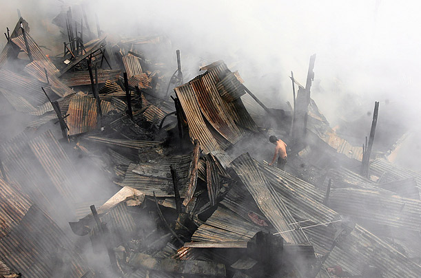 A man tries to recover belongings from his shanty after a fire in Manila.  More than 100 families were left homeless in the fire.