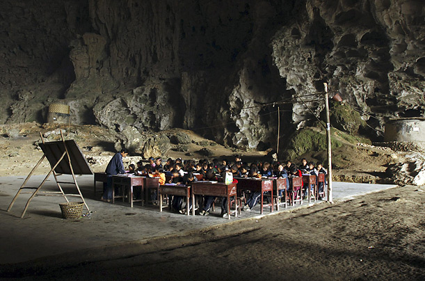 Children attend work at their desks at the Dongzhong primary school in Miao Village, China. The school is built inside a giant natural cave.