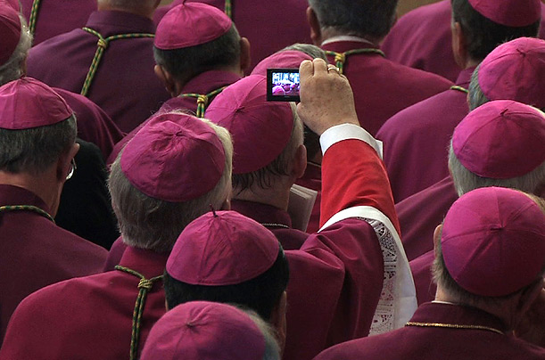 A bishop holds up his digital camera to try to catch a photo of Pope Benedict XVI during the Consistory of Cardinals at St Peter's Basilica in Vatican City.