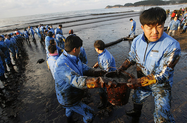 Workers attempt to remove oil from a beach 100 miles southwest of Seoul after a tanker accident off the coast of South Korea.