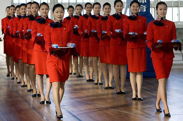 Young women practice their posture and gait at a vocation school in Beijing. They will serve as hostesses during the medal ceremonies at the Olympic Games this summer. 
