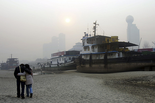 A couple walks past ships left landlocked beside the Yangtze River, the result of a persistent drought.