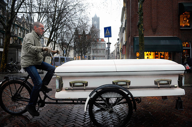 Artist Dirkje Kuik rides his coffin tricycle in the centre of Utrecht, Netherlands. The coffin is used to hold shopping purchases.