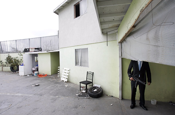 An armed man stands guard at the garage of a home in Tijuana, Mexico, during a police operation to hunt down drug cartel hitmen.   
