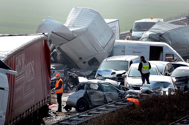 Emergency service workers survey the scene of a mass pile-up on the motorway between Brescia and Cremona, Italy.  Five people were killed and over 50 injured in the incident.