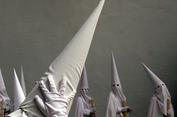 Penitents wait at church for the start of the 'La Paz' brotherhood procession in Seville on the first day of the Holy Week in Spain.