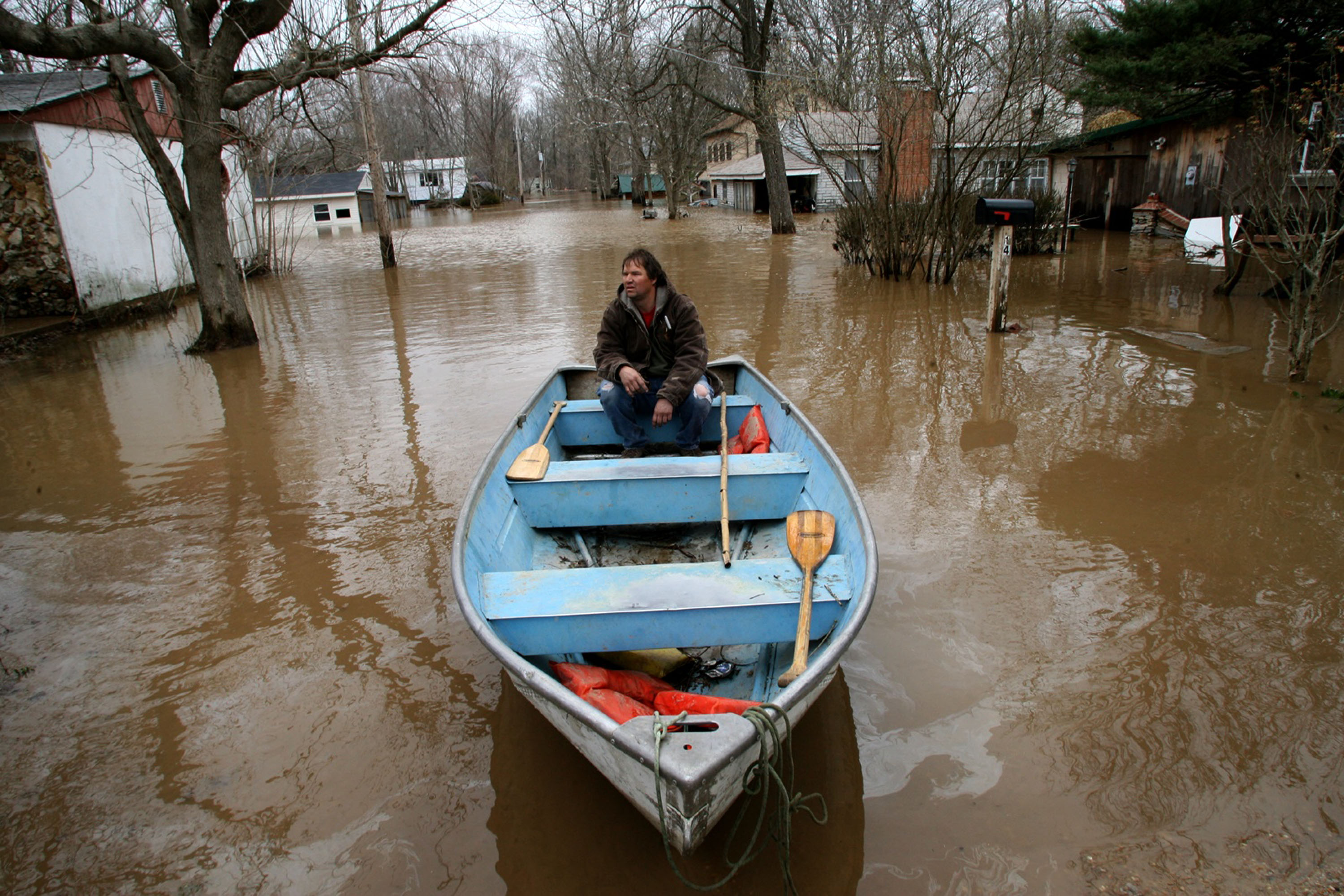 Tim Dodson waits for his daughter to help paddle out to their home to assess the damages caused by a flood, just outside Eureka, Missouri.