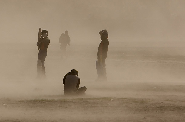 Men are caught in a dust storm while playing cricket at a playground in Kabul. 

