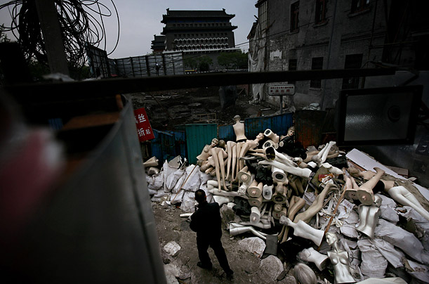 A Chinese man walks by mannequins tossed onto the rubble of demolished shops in Beijing.