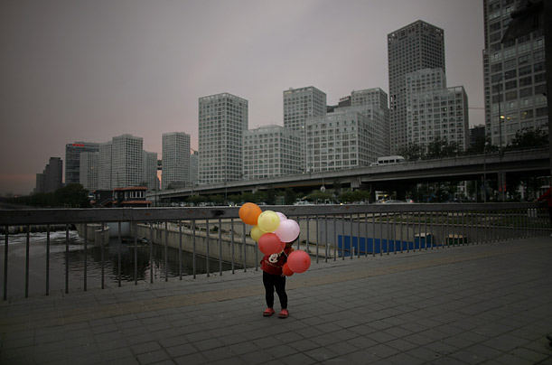 A young Chinese girl holds balloons on a bridge in Beijing.