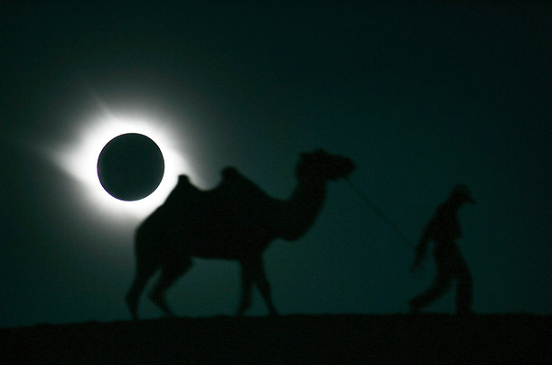 A man and his camel walk past a solar eclipse in Gaotai, Gansu province in China.