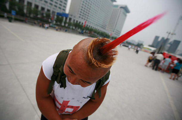 A young man from Harbin shows off his hair style outside the National Aquatics Center, also known as the Water Cube, in Beijing, China