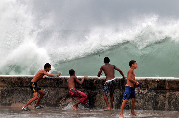 Kids play in the mist of waves created in the wake of Hurricane Ike in Havana, Cuba's El Malecon.