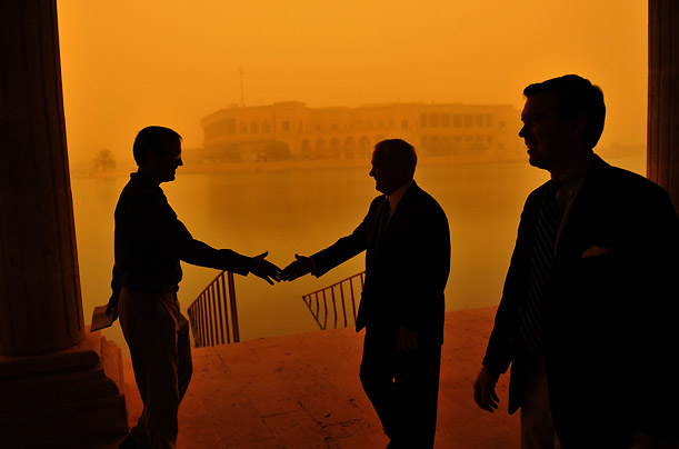 With a sandstorm blowing behind him, Defense Secretary Robert Gates greets a reporter on his way to a television interview at Camp Victory in Baghdad.