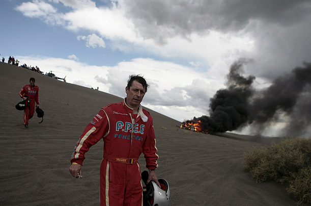 Belgians Christian Lavieille, left, and Jean-Paul Forthomme, right, walk past their burning vehicle after an accident forced them out of the Rally Dakar Argentina-Chile 2009 in Dunas del Nihuil, Argentina.

